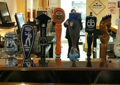 Close-up of seven distinct beer tap handles on a bar.