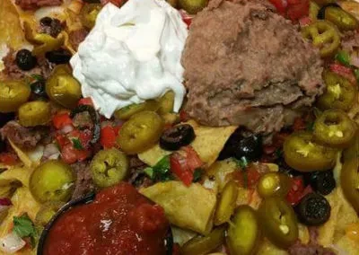 Loaded nachos with meat, sour cream, beans, and salsa, overhead view.