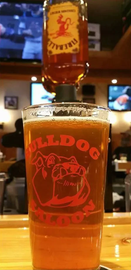 Inverted Fireball bottle pouring into a Bulldog Saloon glass on a bar.