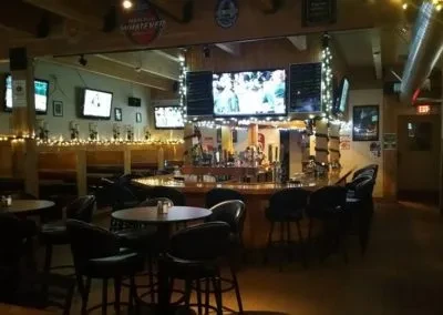 Cozy pub interior with U-shaped bar, beer taps, and sports TVs.