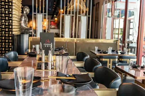 Modern upscale restaurant interior with dining tables, chairs, and a Buddha statue.