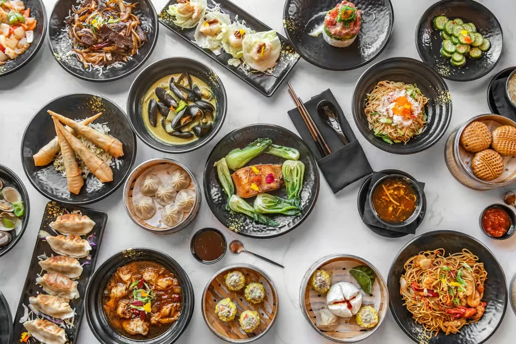 Flat lay of diverse, meticulously arranged Asian dishes with chopsticks.