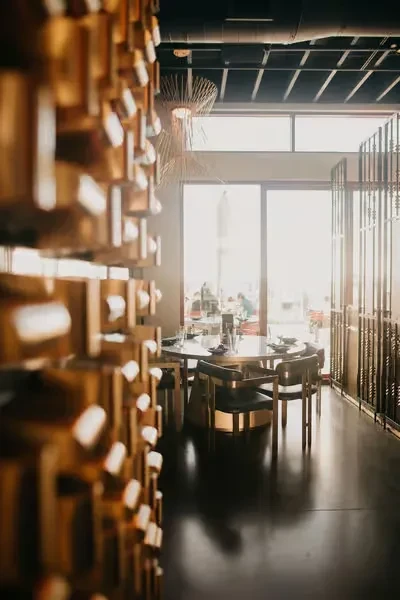 Modern restaurant interior: round table, four chairs, dark plates, spiky chandelier.