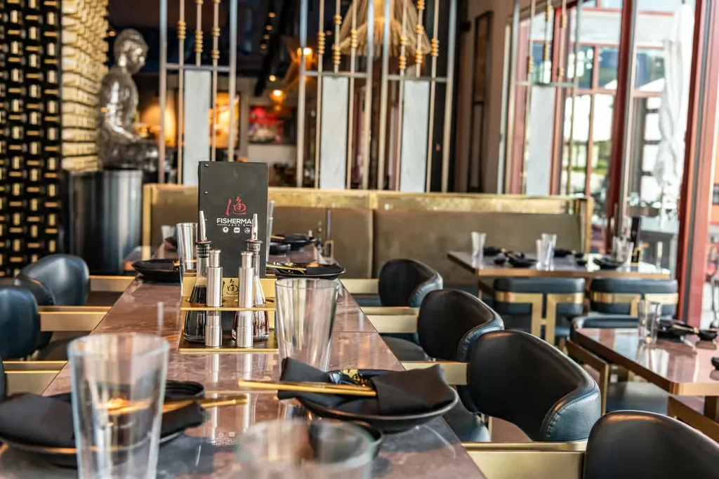 Modern restaurant interior with FISHERMAN menu, chopsticks, and Buddha statue.