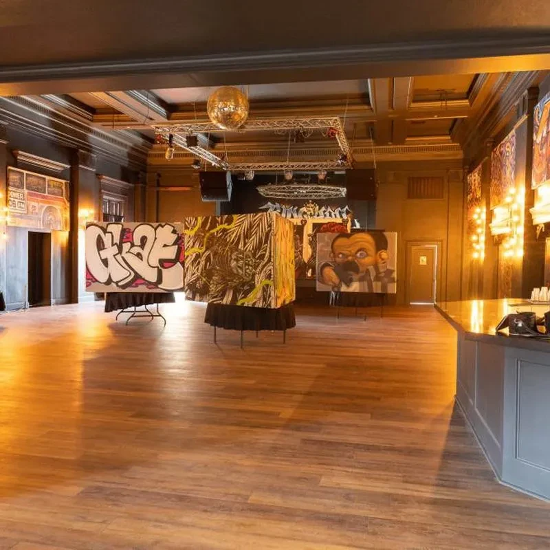 Spacious, dark event venue with disco ball, bar, and contemporary art.