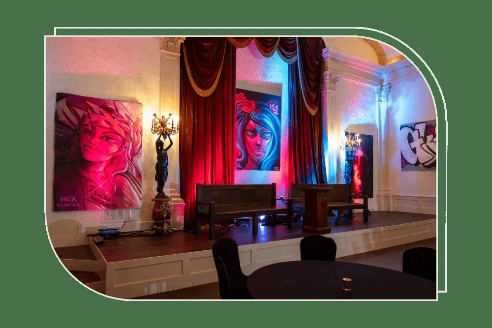 Dramatic stage, statue, and modern artworks illuminated by colorful spotlights.