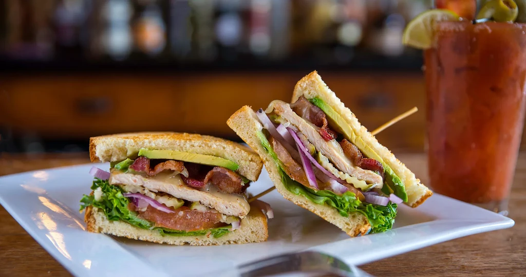 Diagonally cut club sandwich showing chicken, bacon, and avocado.