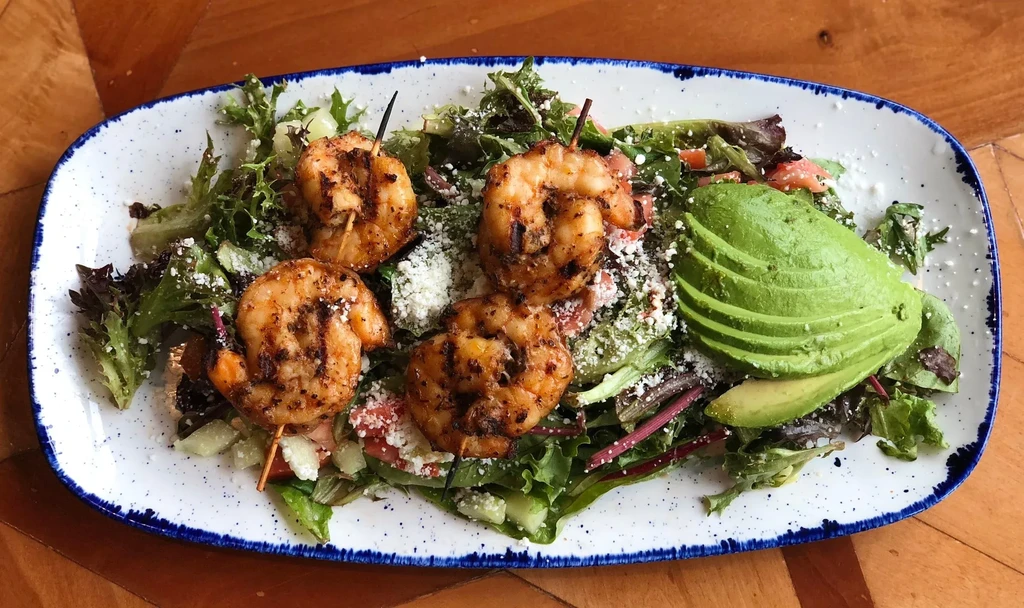 Grilled shrimp salad with crumbled cheese and fanned avocado.