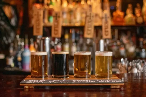 Four different beers on a labeled wooden paddle.