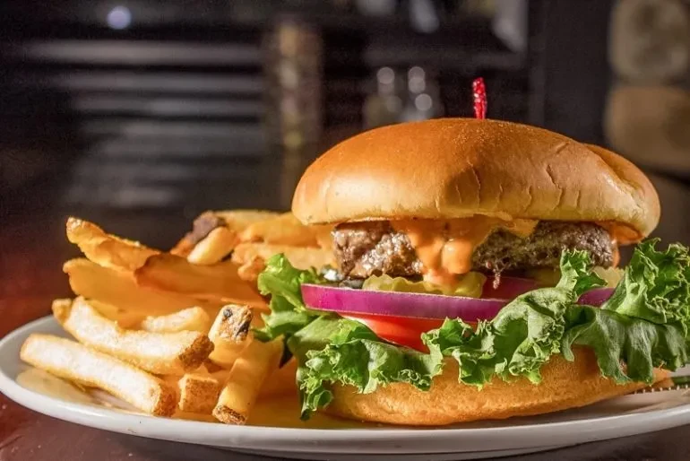 Gourmet burger with melted cheese, pickles, and natural-cut fries.