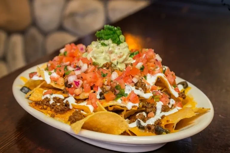Close-up: loaded nachos with beef, melted cheese, pico, and guacamole.