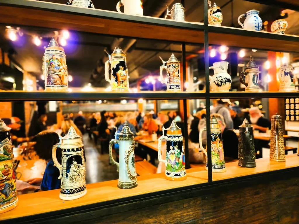 Ornate ceramic and metal beer steins displayed on rustic shelves.