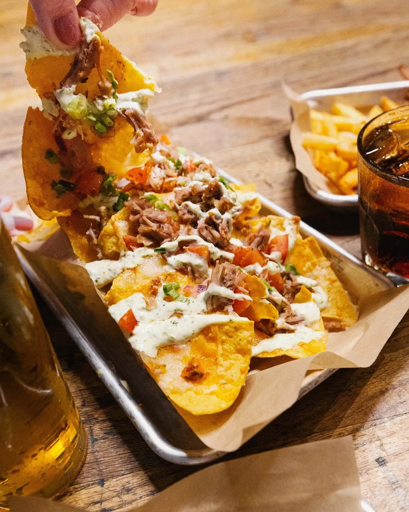 Heavily loaded pulled meat nachos with sauce, tomatoes, and green onions.