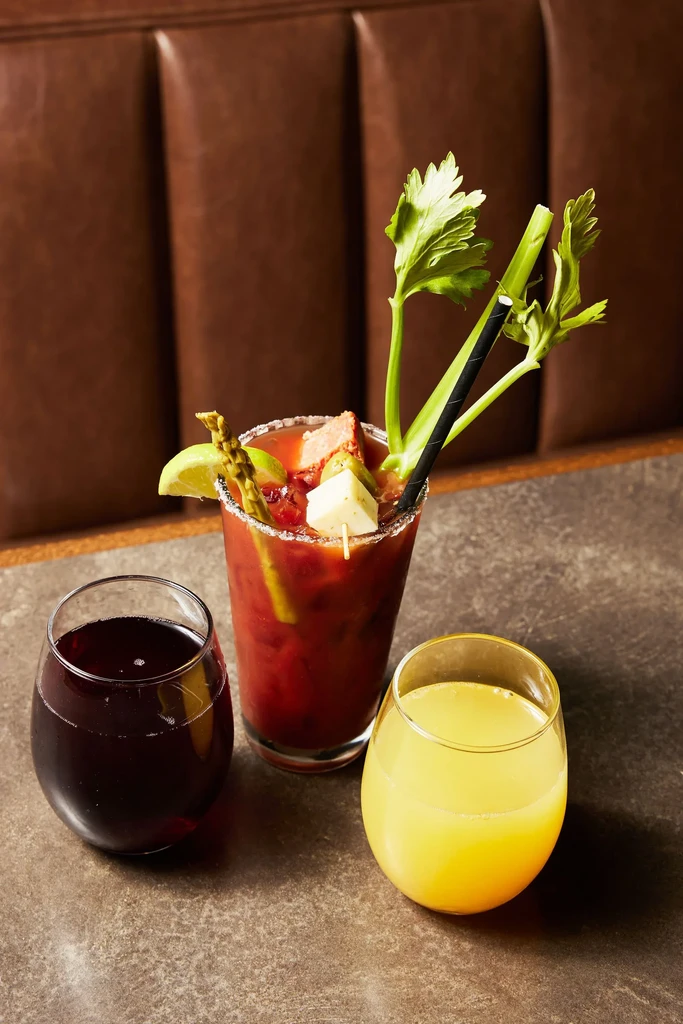 Garnished red drink, dark red and yellow drinks on a restaurant table.