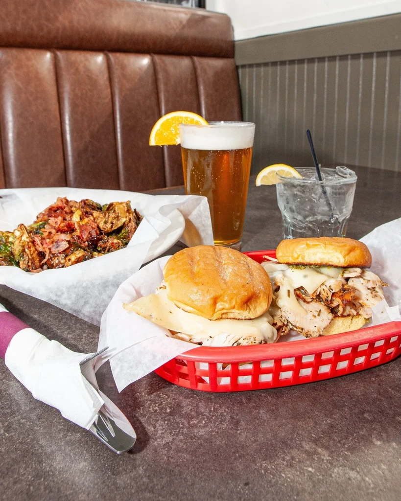 Two open-faced sandwiches, roasted vegetables, beer, and water.