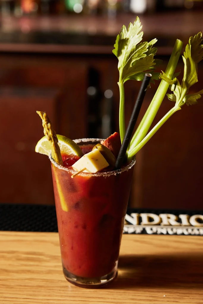 Elaborately garnished Bloody Mary cocktail with celery, asparagus, and cured meat.