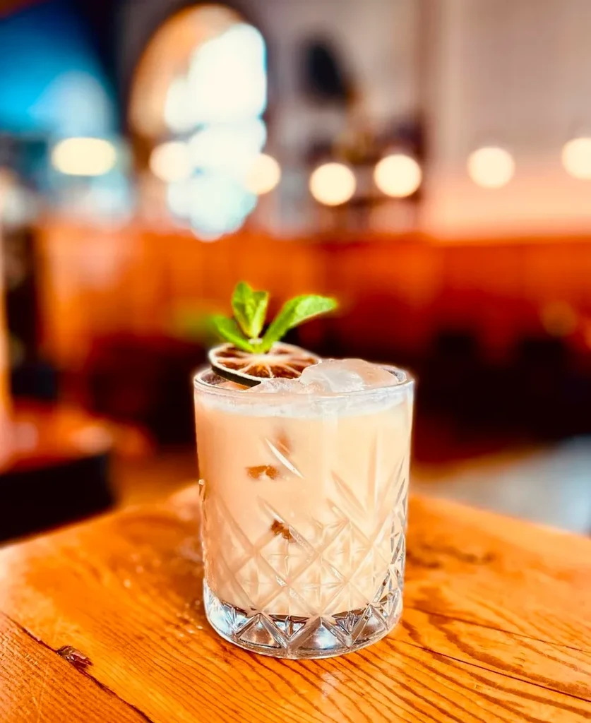 Creamy cocktail in diamond-patterned glass with citrus and mint.