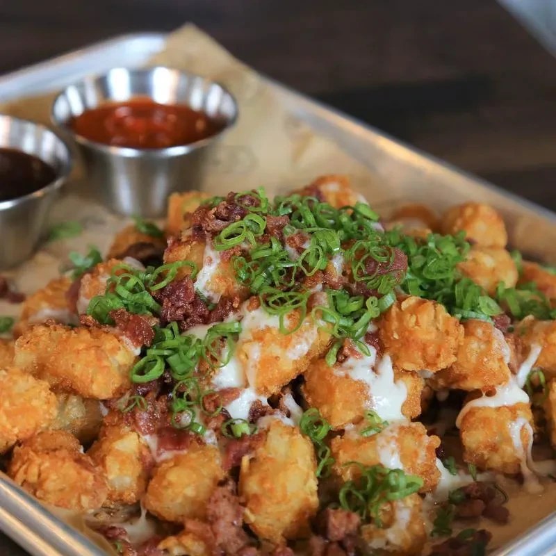 Crispy tater tots topped with creamy sauce, bacon, and green onions.