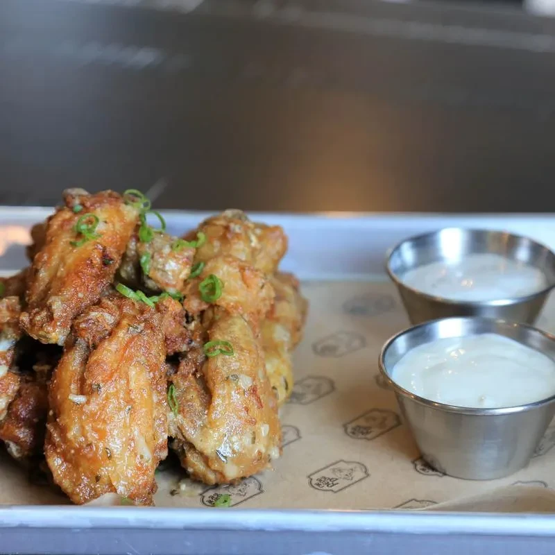 Crispy golden-brown fried chicken wings, green onions, and two dipping sauces.