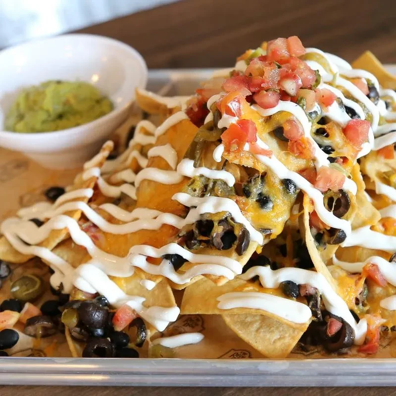 Nachos topped with melted cheese, black beans, sour cream, and pico de gallo.