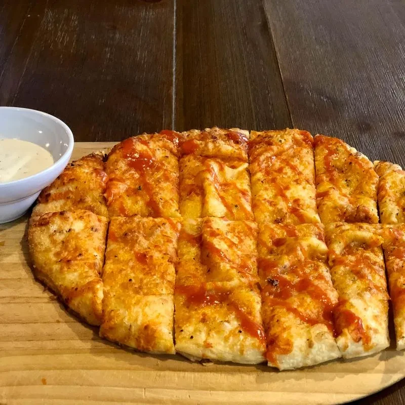 Rectangular bread sticks with cheese, red sauce, herbs, and dipping sauce.