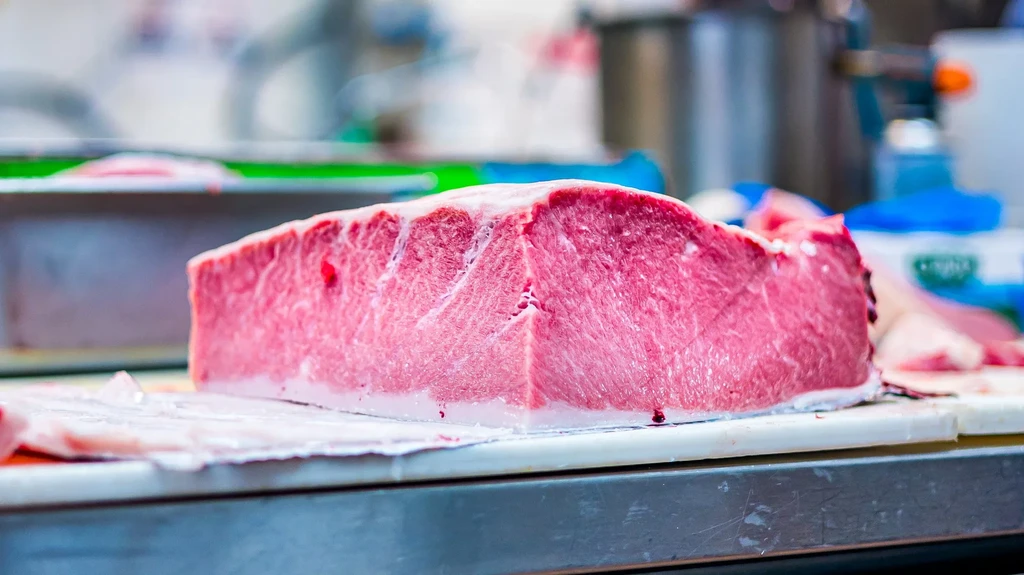 Deep red, marbled tuna block on a white cutting board.