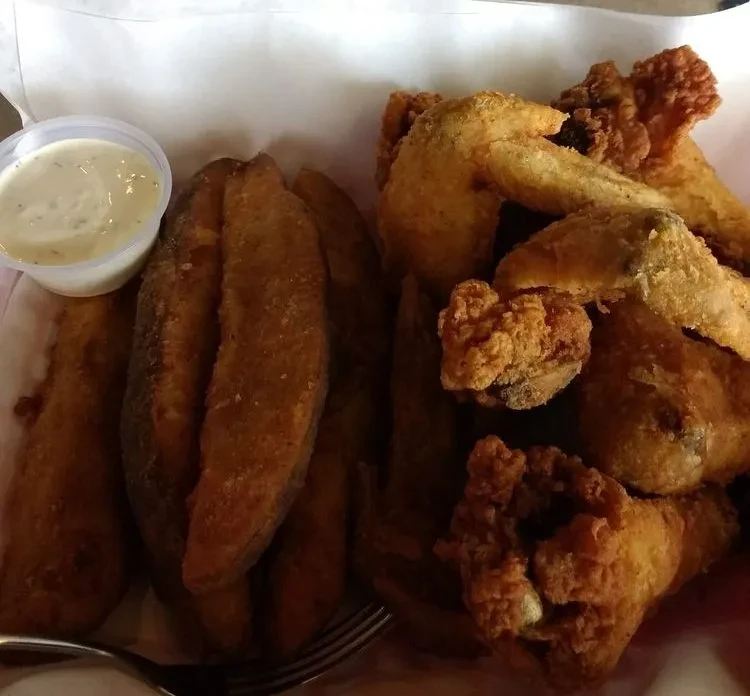 Overhead view of crispy fried chicken wings, potato wedges, and sauce.