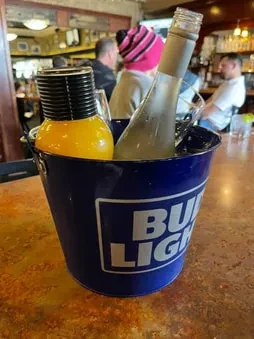 Blue Bud Light bucket with two bottles on a bar counter.