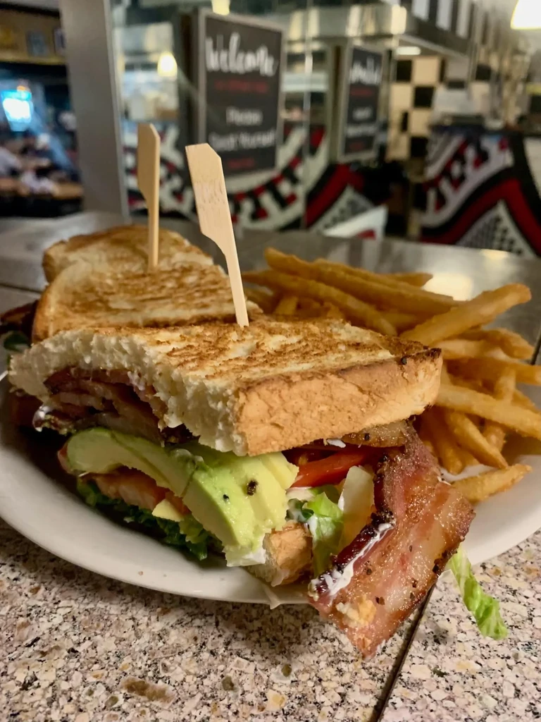 Toasted bacon avocado sandwich and golden fries served in a diner.