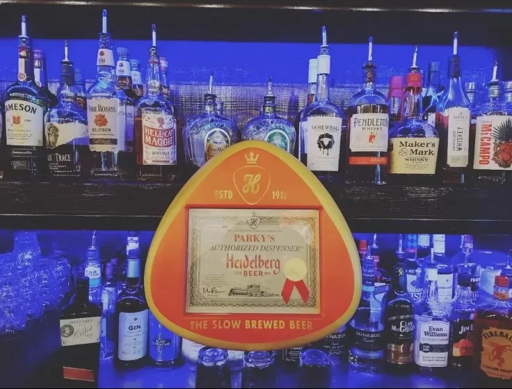Blue-lit bar shelves with liquor bottles and a Parky's Beer sign.
