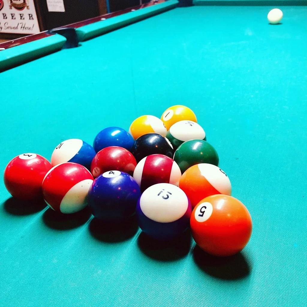 A full rack of numbered billiard balls on a turquoise pool table.