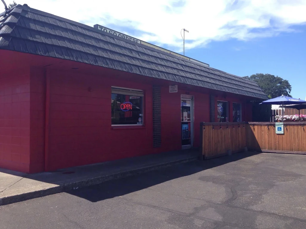 Bright red restaurant with 'OPEN' sign and shaded outdoor patio.