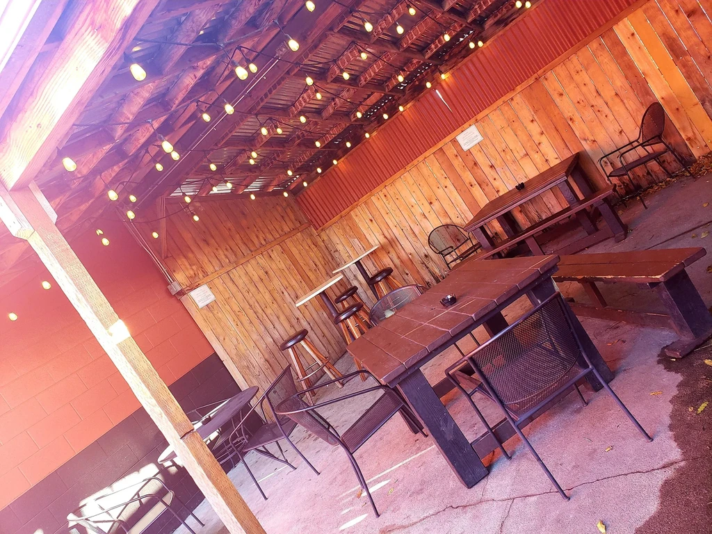 Rustic restaurant patio with wooden walls, string lights, and seating.
