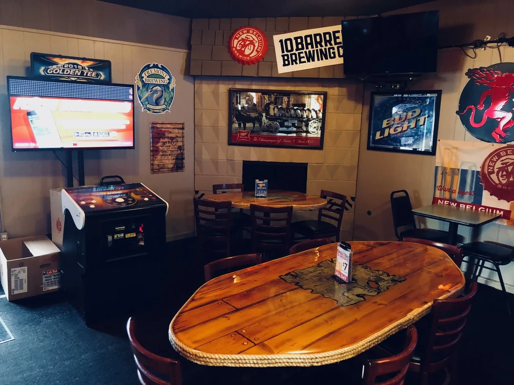 Empty bar with wooden tables, multiple TVs, and brewery brand signs.