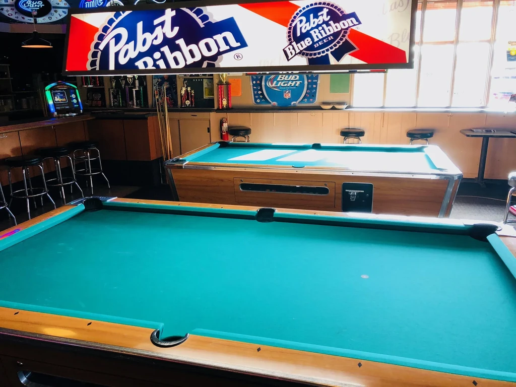 Casual bar interior with two prominent teal-felted pool tables.
