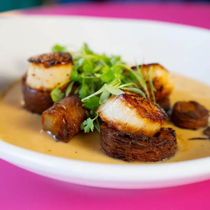 Perfectly seared scallops, crispy potatoes, creamy sauce, and green herbs.