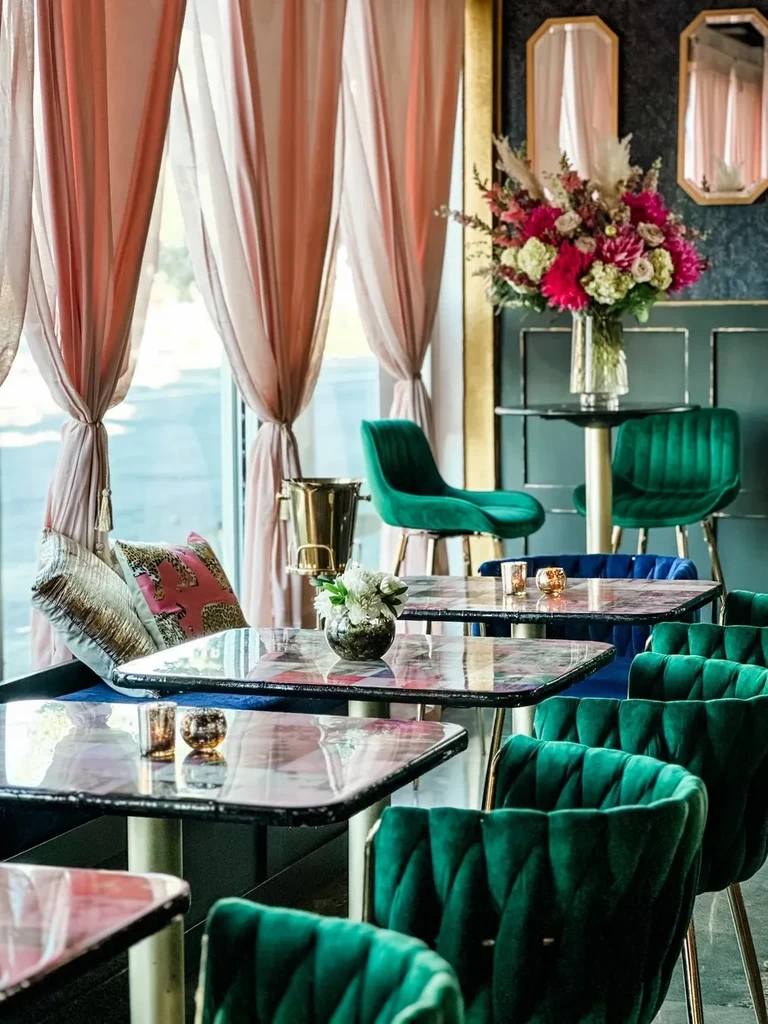 Luxurious restaurant interior with emerald velvet chairs and colorful tables.