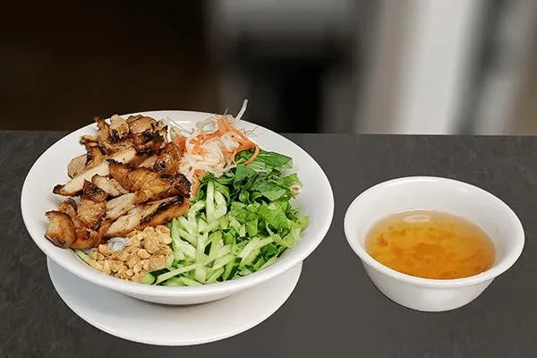 Vietnamese vermicelli bowl with grilled pork, fresh vegetables, and dipping sauce.
