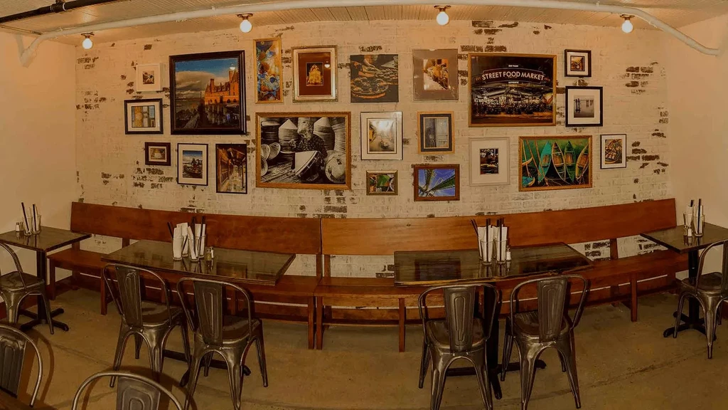 Industrial restaurant interior: art gallery wall, dark furniture, warm lighting.