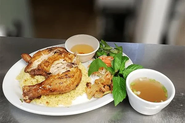 Roasted chicken, yellow rice, pickled vegetables, herbs, sauce, and broth.