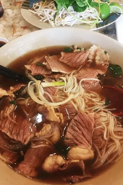 Overhead close-up of Vietnamese beef pho with noodles, beef, and broth.