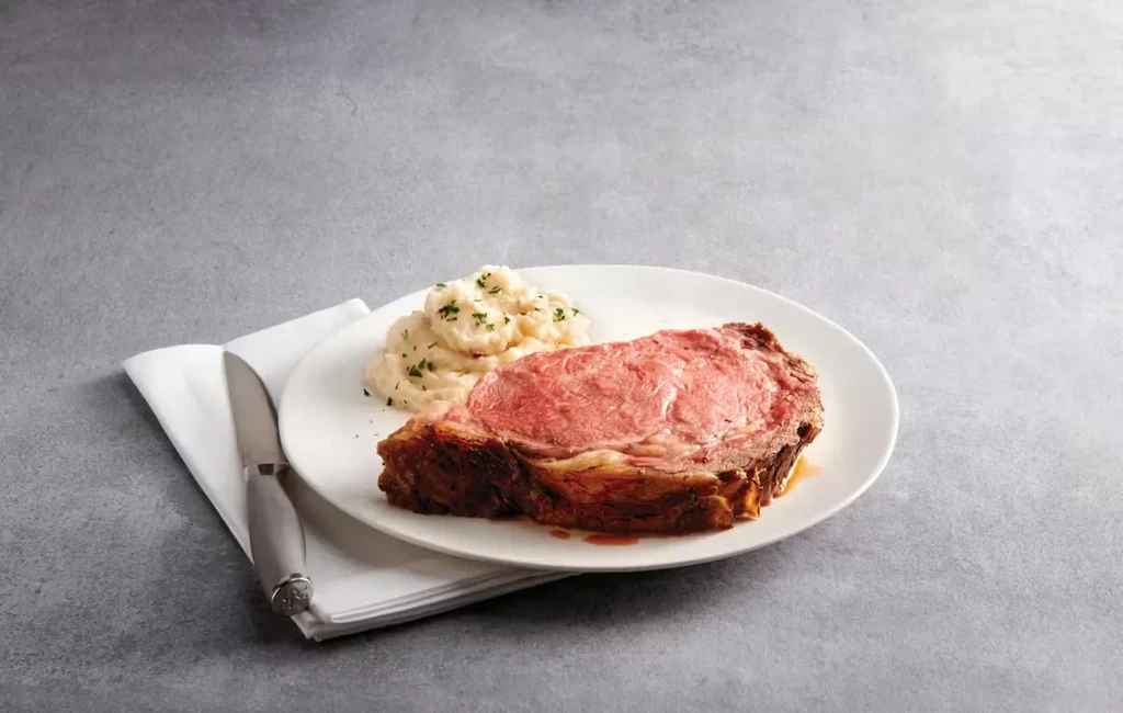 Seared medium-rare prime rib with mashed potatoes and herbs.