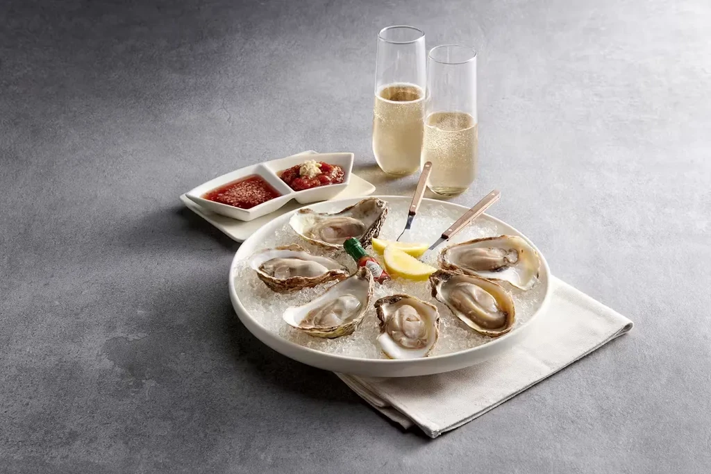 Fresh oysters on ice with champagne, lemon, and sauces.