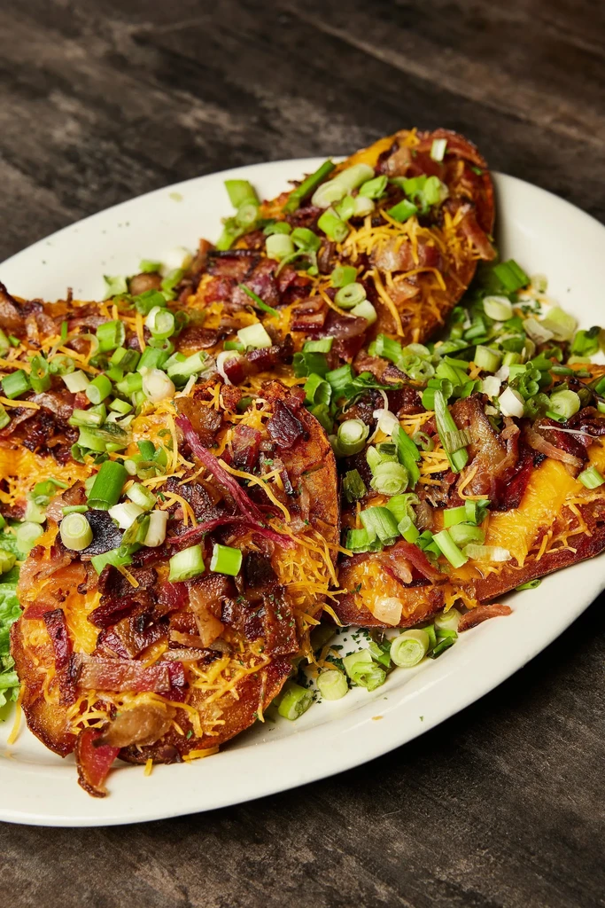 Crispy loaded potato skins with melted cheese, bacon, and green onions.