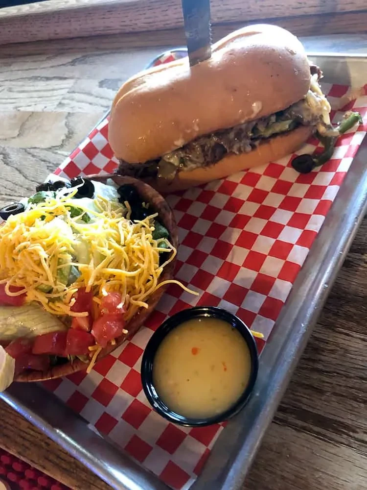 Sandwich and large taco salad on a checkered metal tray.
