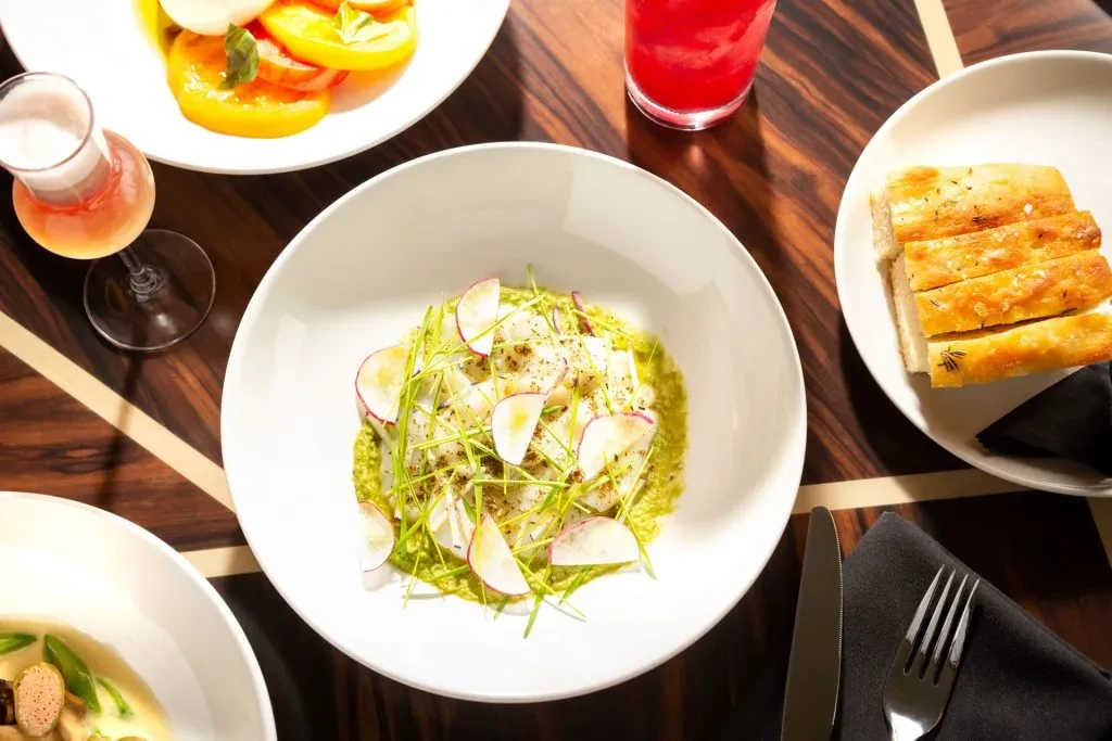 Top-down view: elegant restaurant table with white dish on green sauce.