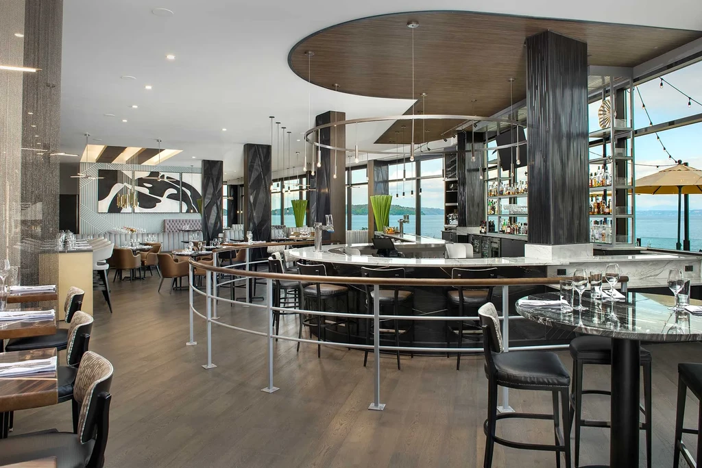 Luxurious restaurant interior with curved bar, dining tables, and water view.