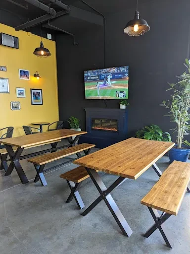 Modern industrial restaurant interior with a yellow accent wall.