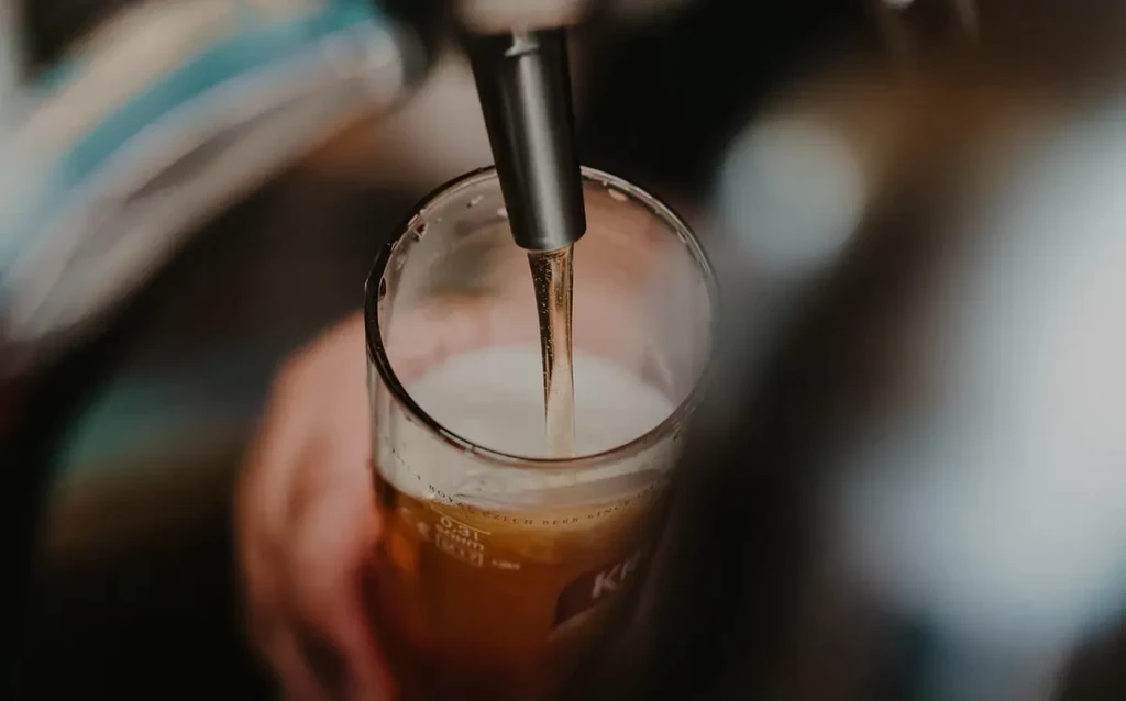 Close-up of golden beer pouring from a tap into a glass.