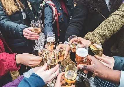 Hands toast with champagne flutes and beer glasses.
